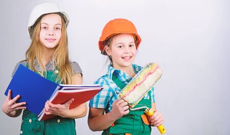 Little kids in helmet with tablet and roller. Labor day. 1 may. small girls repairing together in workshop. Foreman inspector. Repair. school project. successful team. successful businessの写真素材