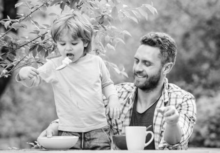 Father son eat food and have fun. Food habits. Little boy with dad eating food natureの写真素材