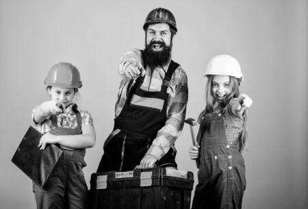 construction worker assistant. Builder or carpenter. Repairman in uniform. Foreman. Family teamwork. Repair. Father and daughter in workshop. Bearded man with little girls. Every detail is importantの写真素材