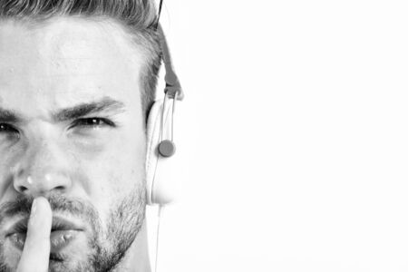 relax playlist. sexy muscular man listen music from playlist. man relax in earphones isolated on white. unshaven man relax with favorite song. man with hush gesture listening to musicの写真素材