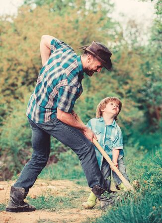 rich natural soil. Eco farm. Ranch. new life. soils and fertilizers. small boy child help father in farming. father and son planting family tree. earth day. Dig grounf with shovel. Helping in gardenの写真素材