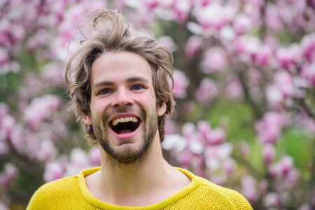 feel refreshed. easter. sakura smell. enjoy good weather. allergy. happy man at blooming magnolia flower tree. spring holiday. healthy youth. relaxing in morning. man near flowering treeの写真素材