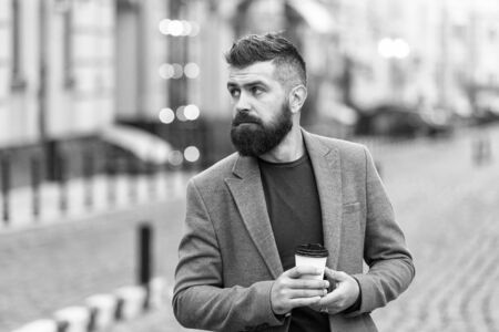 Get some rest after hard day. Man bearded hipster drink coffee paper cup. Businessman well groomed enjoy coffee break outdoor urban background. Thoughtful but relaxed. Walk and enjoy fresh hot coffeeの写真素材