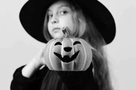 Kid in black witch hat and dress. Girl with pumpkinの写真素材