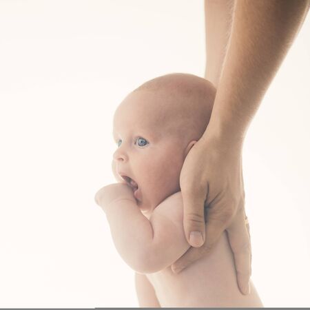 Childhood, parentship and first steps concept. Infant learning to walk with fathers or mothers help.