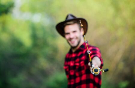 fishing rod selective focus. happy fisherman in hat blurred. western portrait. Vintage style man. Wild West retro cowboy. fly fishing. man checkered shirt on ranch. fisher hold fish net. hobbyの写真素材