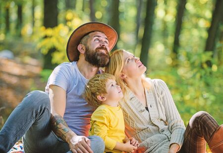 Happy son with parents relax in autumn forest. Mother, cowboy father love their little boy child. Spring mood. Happy family day. Sunny weather. Healthy food. Family picnic. Spring everywherの写真素材