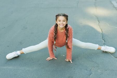 Pilates for health resolution. Small girl do splits outdoor. Little child enjoy pilates workout. Pilates stretching and flexibility exercises. Pilates or yoga for beginnersの写真素材