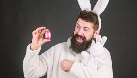 Easter activities concept. Egg hunt game. Guy bearded hipster cute gentle bunny with long white ears...