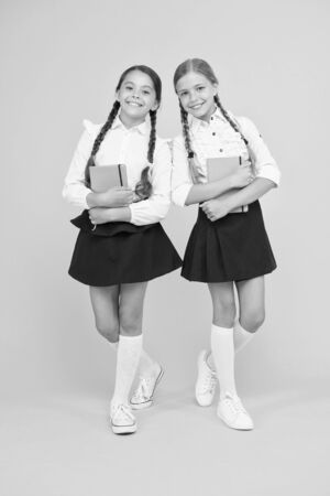 good grades. literature lesson. childrens literature. small girls kids with book. reading and writing. back to school. Classmates at book store or library. happy girls study with workbookの写真素材