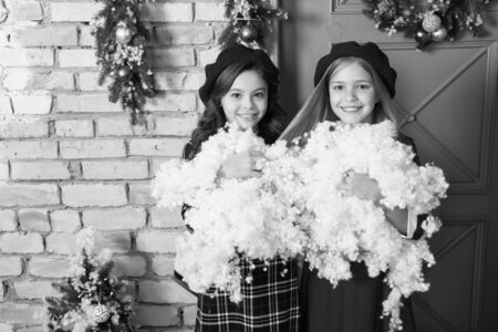 Warm winter wishes. Happy children celebrate Christmas and new year. Small children with artificial snow. Small girls with Christmas decoration. Winter fun. Childhood games on winter holidaysの写真素材
