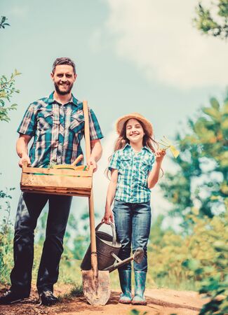 father and daughter on rancho. summer farming. farmer man with little girl. garden tools, shovel and watering can. kid worker with dad. family bonding. spring country side village. Flower wateringの写真素材