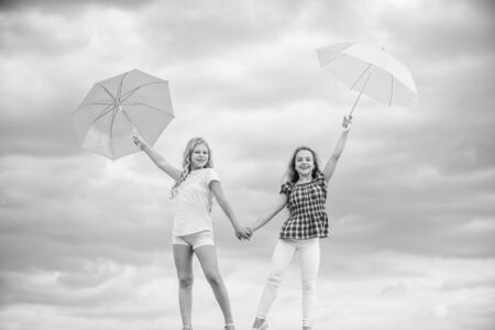 Exploring the world together. autumn season. rainy weather forecast. fall kid fashion. protected at autumn day. happy small girls with umbrella. positive and bright mood. best friends. school timeの写真素材