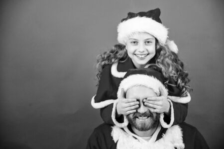My dad is santa claus. Belief in santa constitutes most magical part of childhood. Guess who. Surprise concept. Girl child and bearded father wear santa costume. How to be santa claus parents guideの写真素材