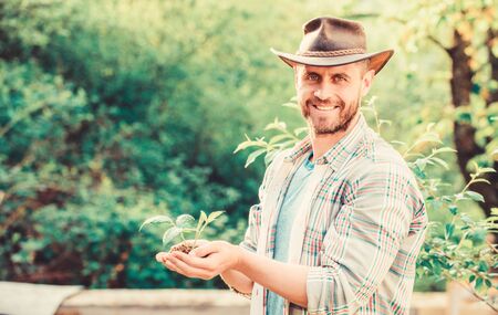 happy earth day. Eco living. Eco farm worker. Earth day. muscular ranch man in cowboy hat care plants. farming and agriculture cultivation. Gardening. successful farmer hold plant in ground in handsの写真素材