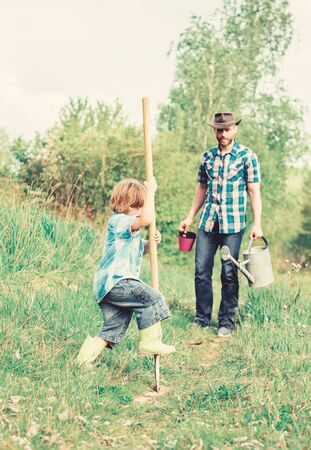 rich natural soil. Eco farm. Ranch. happy earth day. Dig grounf with shovel. new life. soils and fertilizers. small boy child help father in farming. father and son planting family tree. Pulling weedの写真素材