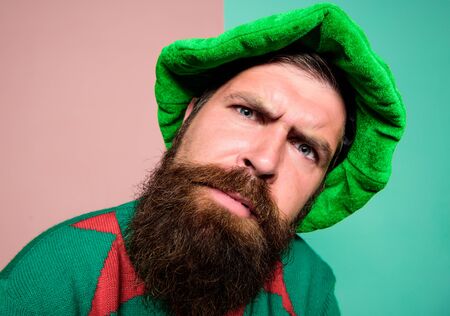 Who is there. Picky man looking at camera. Bearded elf. Winter carnival. St Patricks day. Hipster with beard wearing green costume for party. Christmas elf. Elf concept. Traditions or customsの写真素材