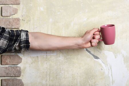 male hand holding cup on brick and textured backgroundの写真素材