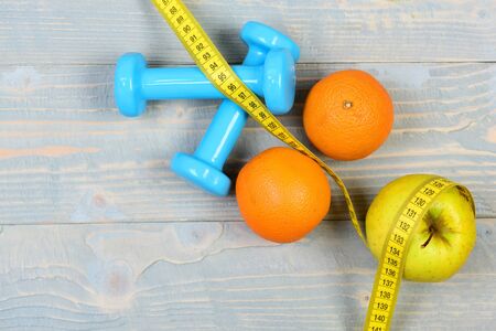 sport equipment concept, dumbbells weight with measuring tape and fruitの写真素材
