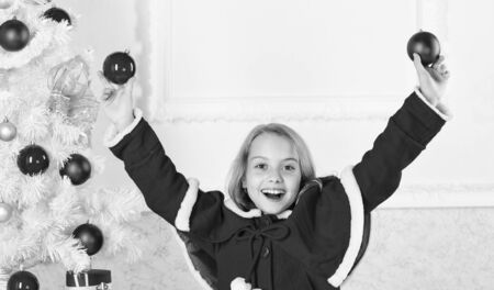 Girl smiling face hold balls ornaments white interior background. Let kid decorate christmas tree. Favorite part decorating. Getting child involved decorating. How to decorate christmas tree with kidの写真素材