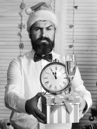 Man with beard holds striped present box with champagne glassの写真素材