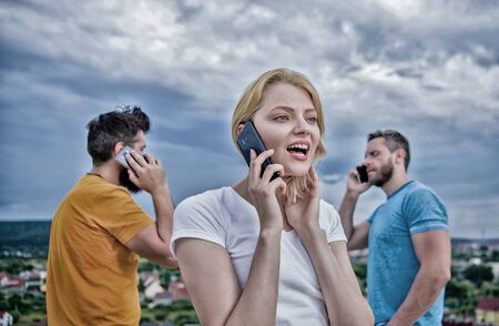 Interacting with one another through technology. Group of friends talking on cell phones. People using mobile communication technology. Modern people with smartphones outdoor. Mobile phone usersの写真素材
