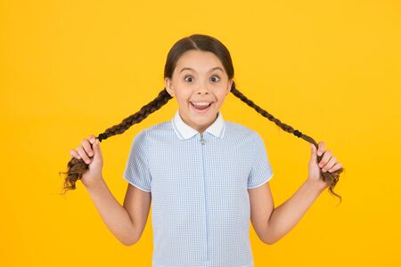 Cute braids. Tender schoolgirl on yellow background. Tidy hairstyle. Little girl with cute braids....