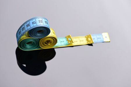 Measuring tape rolls placed on each other on mirror background
