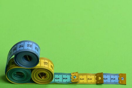 Tape measures of cyan, blue, yellow colors placed in pyramid