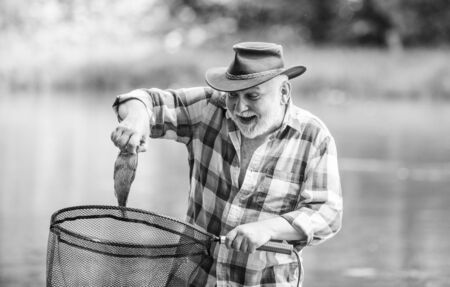 Fish farming pisciculture raising fish commercially. Fisherman alone stand in river water. Man senior bearded fisherman. Fisherman fishing equipment. Hobby sport activity. Pensioner leisureの写真素材