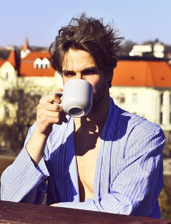 Caucasian macho in blue striped pajamas holding cupの写真素材