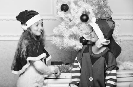 Winter masquerade concept. Merry christmas. Family holiday tradition. Children cheerful celebrate christmas. Siblings ready celebrate christmas or meet new year. Kids christmas costumes santa and elfの写真素材