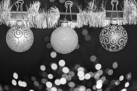 Christmas ornaments concept. Balls with ornaments hang on shimmering tinsel. Pick colorful decor for christmas tree. Tinsel with pinned christmas ornaments on defocused garland lights background.の写真素材