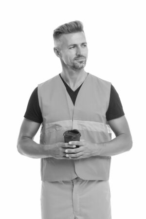 Coffee break concept. Builder enjoy coffee. Strong handsome builder hold coffee cup. Successful engineer. Man protective uniform white background. Worker builder confident drinking coffee and relaxの写真素材