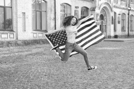 National holiday. Girl cheerful jumping. 4th of July. American tradition. American patriotic people. American woman USA flag outdoors. Patriotic citizen. Vacation and travel. Independence dayの写真素材
