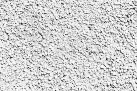 Grainy texture of decorative plaster. Tiny grains little stones in cement or concrete. Vintage decorations. Grainy wall of old building. Grainy surface on sunny day. Architecture facade designの写真素材