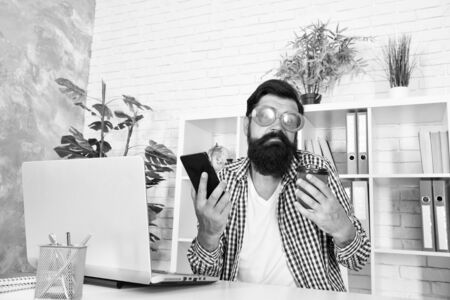 I dont know. Funky man with shrug face holding mobile phone and coffee cup at work. Brutal hipster using his cell phone. Placing order by phone. Video conferencing is as easy as making a phone callの写真素材