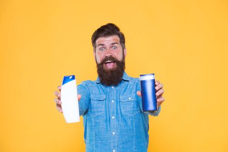 Shampoo for daily use. Skin lotion. Picking proper remedy. Shampoo conditioner. ombine two products for best results. Liquid soap. Bath cosmetics. Man bearded hipster hold shampoo bottles. Hair careの写真素材