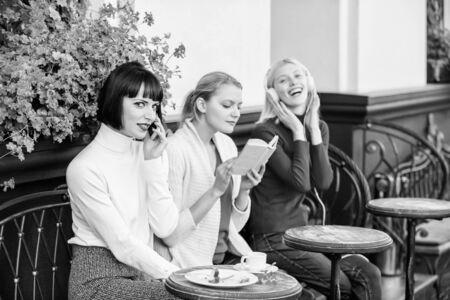 Different interests. Hobby and leisure. Group pretty women cafe terrace entertain themselves with reading speaking and listening. Information source. Female leisure. Weekend relax and leisureの写真素材