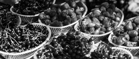 Homegrown berries. Cherries and strawberries in baskets for sell. Farm market. Summer harvest. Red ripe berries. Juicy berries from garden. Buy fresh fruits. Organic berries. Healthy delicious snack.の写真素材