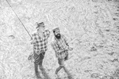 leisure. concept of a rural getaway. hobby. wild nature. two happy fisherman with fishing rod and net. Big game fishing. friendship. father and son fishing. Poaching. Camping on the shore of lakeの写真素材