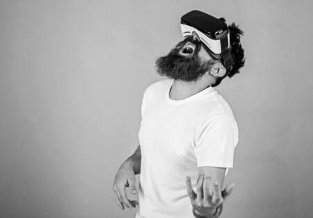 Guy with VR glasses learn to play music on guitar. VR musician concept. Man with beard in VR glasses, green background. Hipster guitarist on enthusiastic face use modern technology for entertainment.の写真素材