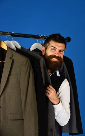 Young businessman choosing suit from row of suitsの写真素材