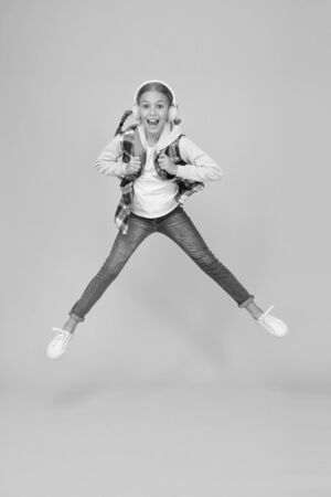 Energetic and enthusiastic. Energized small girl jump high with energetic power. Active kid back to school in energetic mood. Energetic little child in motion yellow backgroundの写真素材