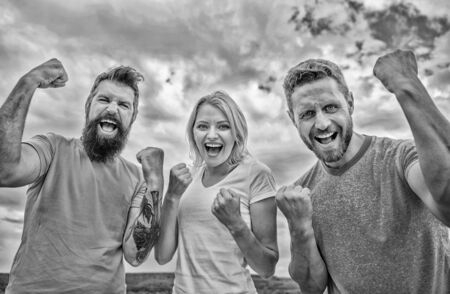 Celebrate success. We can do it. Ways to build successful team. Behaviors of winner team. Woman and men look successful celebrate victory sky background. Threesome stand happy with raised fistsの写真素材