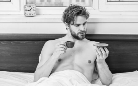 Young man stretching while waking up in the morning. Stretch after wake up in the morning. Portrait of man yawns and stretches in bed.の写真素材