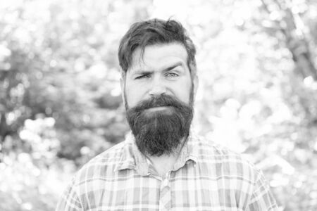 Man bearded hipster green trees background. Guy relax in summer nature. Eco lifestyle. United with environment. Handsome lumberjack. Man beard and mustache in summer forest. Summer vacation conceptの写真素材