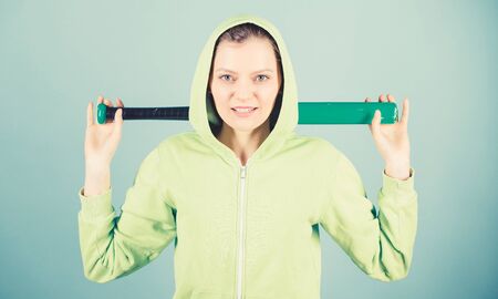 Girl hooded jacket hold baseball bat blue background. Baseball female player concept. She is dangerous. Sport game. Woman play baseball game or going to beat someone. Woman in baseball sportの写真素材