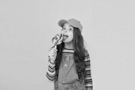 Sugar diet. Sweet candy. My style is colorful. All colors of rainbow. Bright life. Happy childhood. Kid stylish modern child licking lollipop candy. Sweets and dessert concept. Happy kid with candyの写真素材
