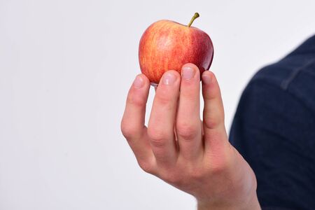Apple fruit isolated on light grey background, defocused. Male hand holds orange apple. Food and healthy lifestyle concept. Apple in fresh and juicy color.の写真素材